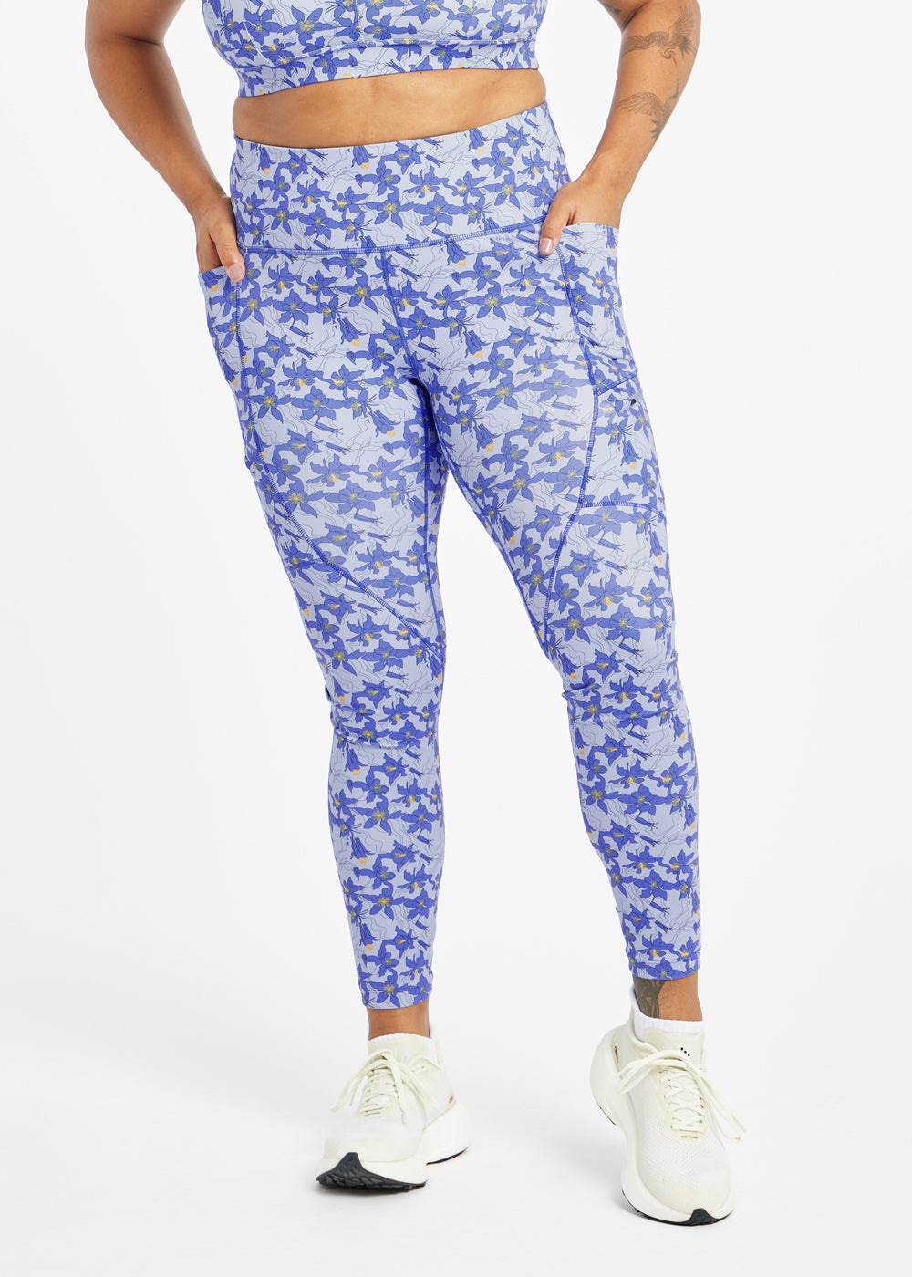 Woman wearing blue with blue flower print  running tights in size 12, alternate front view