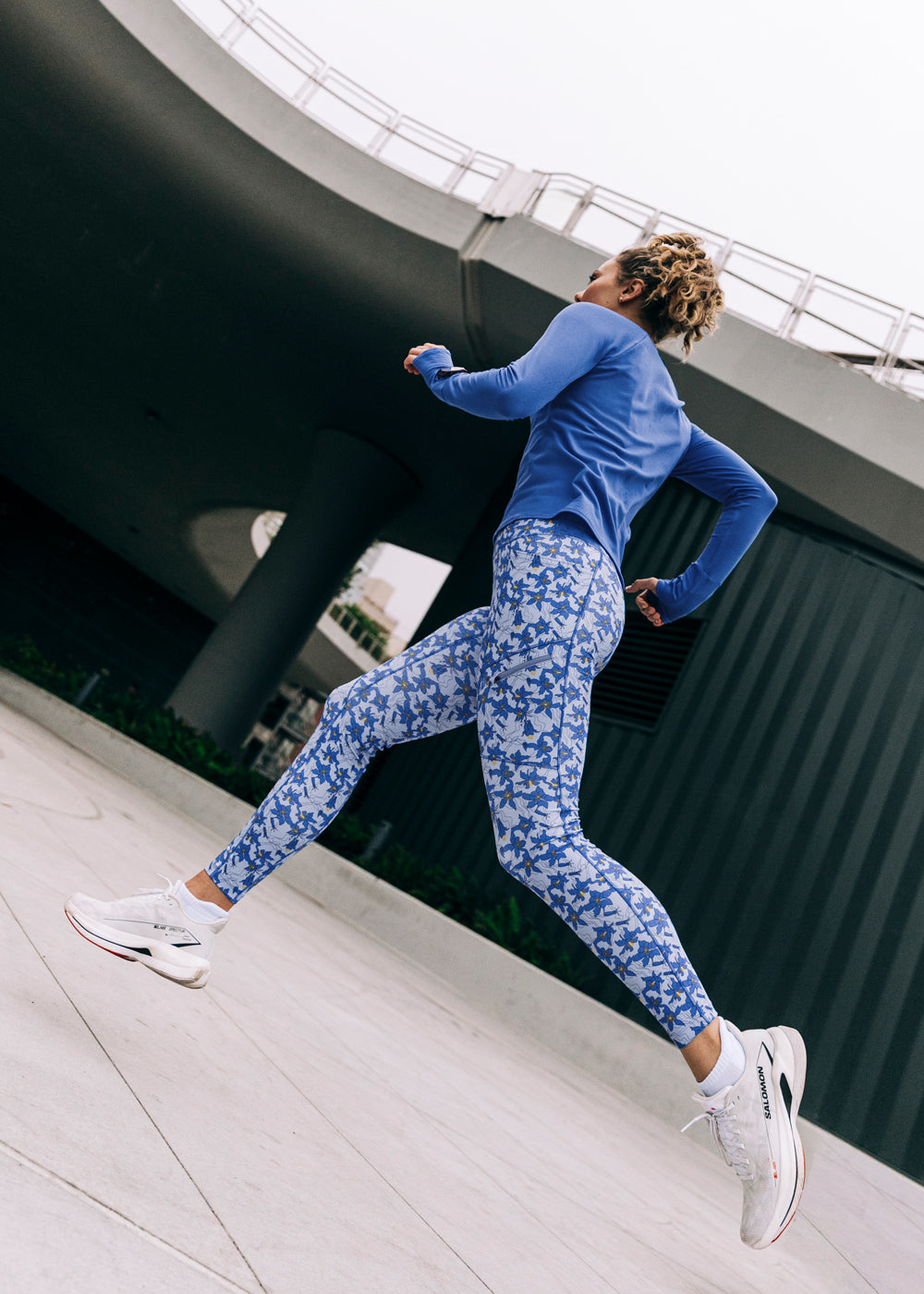 Woman running outside in a blue long sleeve and blue with blue flower print  running tights
