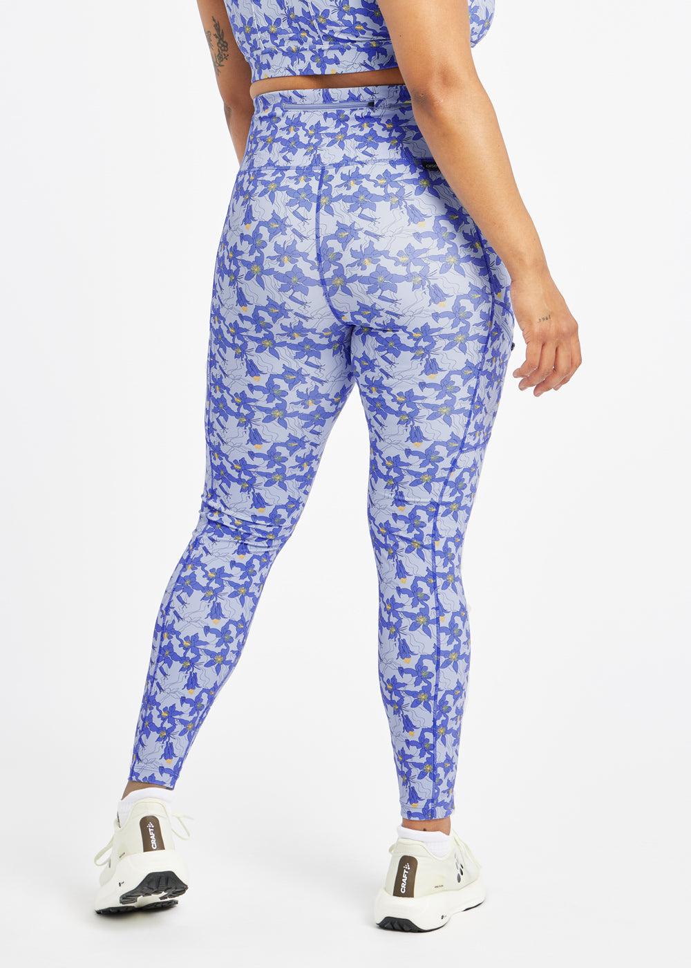 Woman wearing blue with blue flower print  running tights in size 12, back view